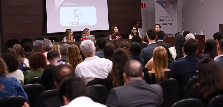 Auditório lotado em evento da Comissão de Advocacia Criminal da OAB com logotipo da Rockham Marketing Jurídico projetado na tela como patrocinador oficial